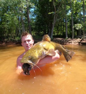 Noodler in purple shirt with large catfish catch