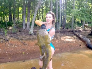 Noodler holding catfish in forest stream